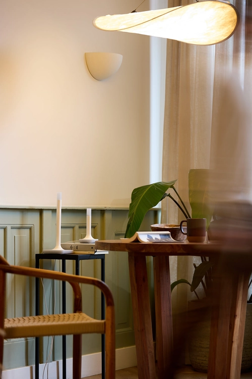 A wide lifestyle shot of a room, with the Home Assistant Connect ZBT-2 device next to a Home Assistant ZWA-2 on a black side table against a green paneled wall.